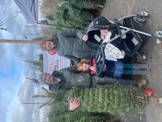 A family stands with their Christmas tree.